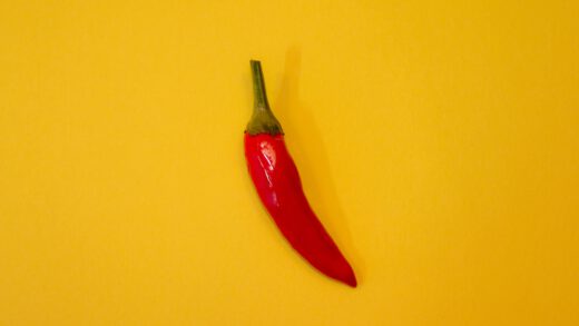 Mała czerwona papryczka chili z zielonym ogonkiem na żółtym tle
