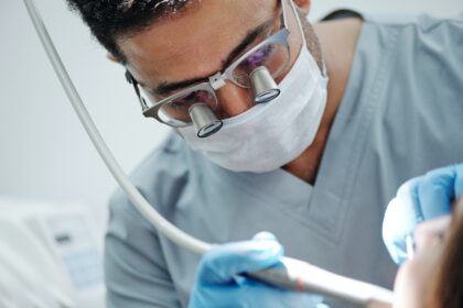 Mężczyzna pracuje jako dentysta i kontroluje zęby swojemu pacjentowi