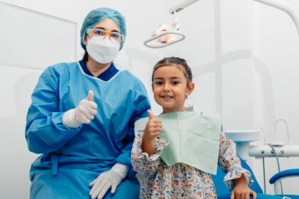 Uśmiechnięta dziewczyna stoi obok swojego stomatologa