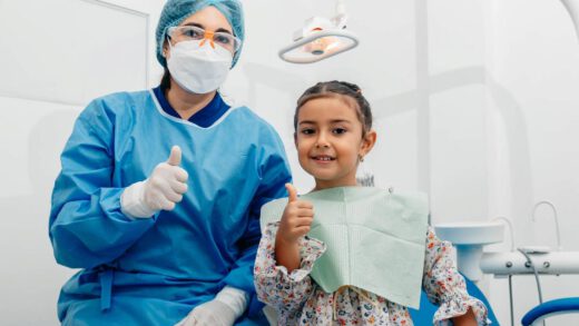 Uśmiechnięta dziewczyna stoi obok swojego stomatologa